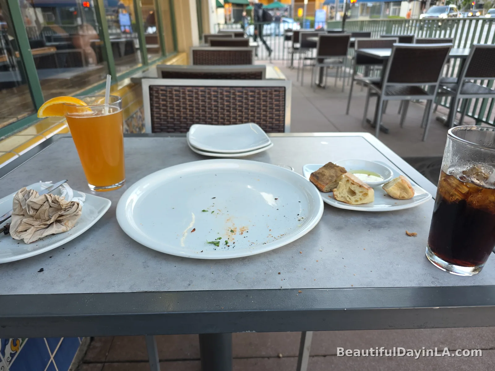 An empty plate after finishing the BBQ Chicken Pizza, with drinks on the patio table