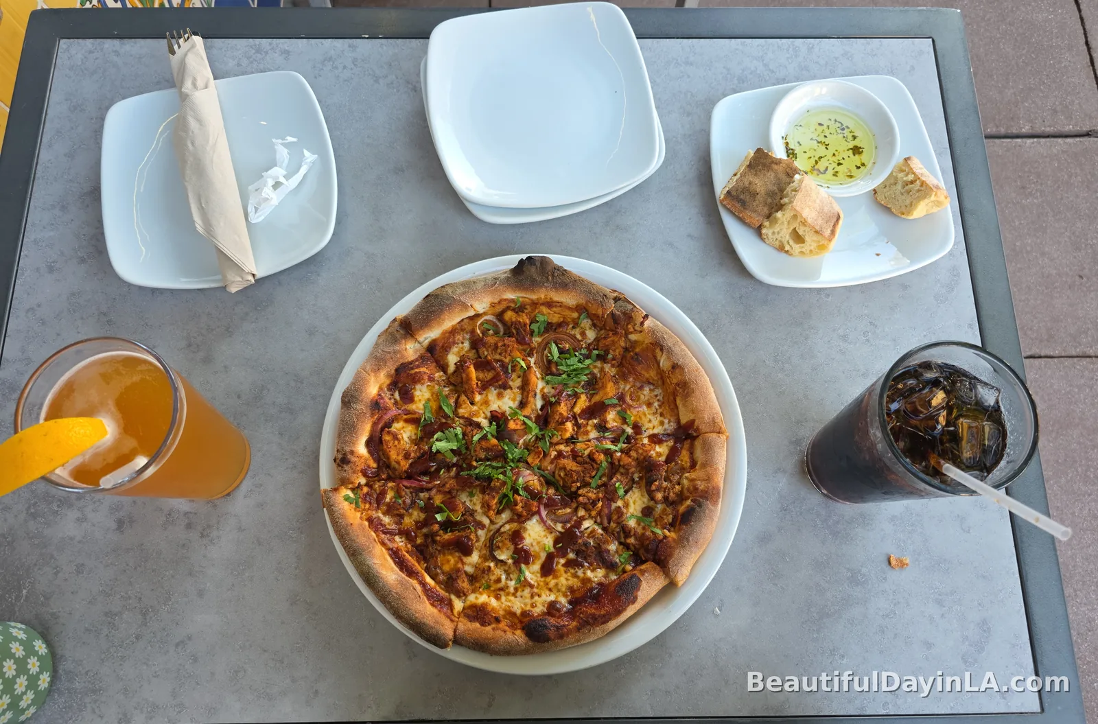 A whole Original BBQ Chicken Pizza on a white plate at California Pizza Kitchen