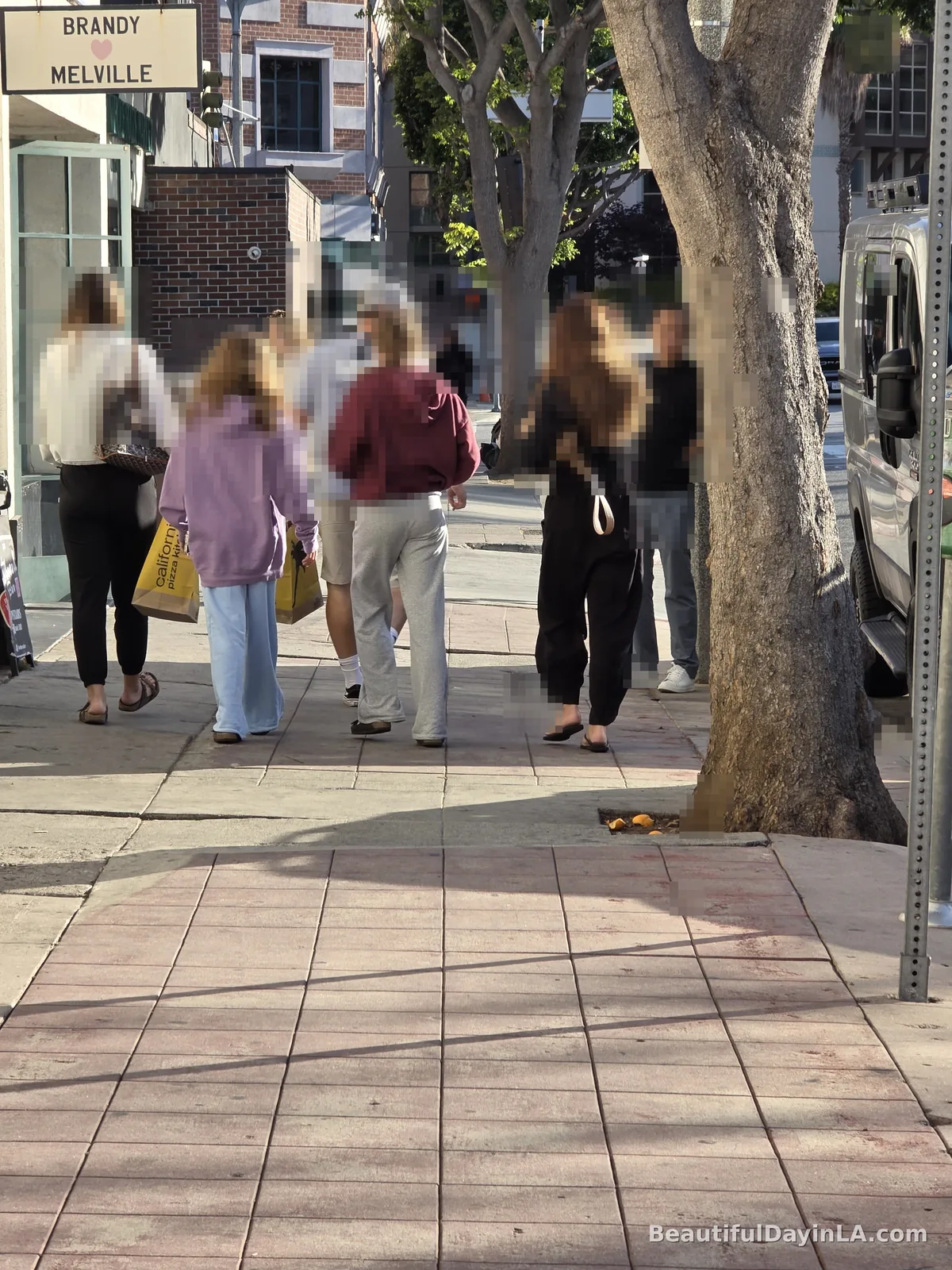 Families and shoppers walking along a Westwood Village sidewalk on a Sunday evening